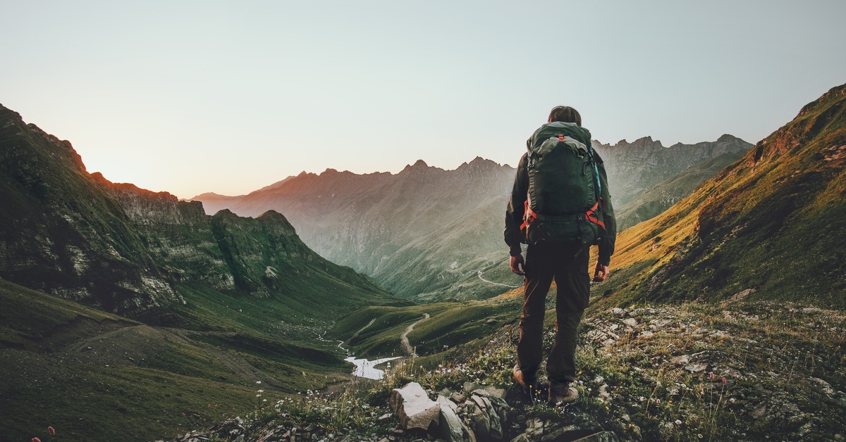 A person standing in a valley, mountains on either side of them. The valley goes deeper into the background.
