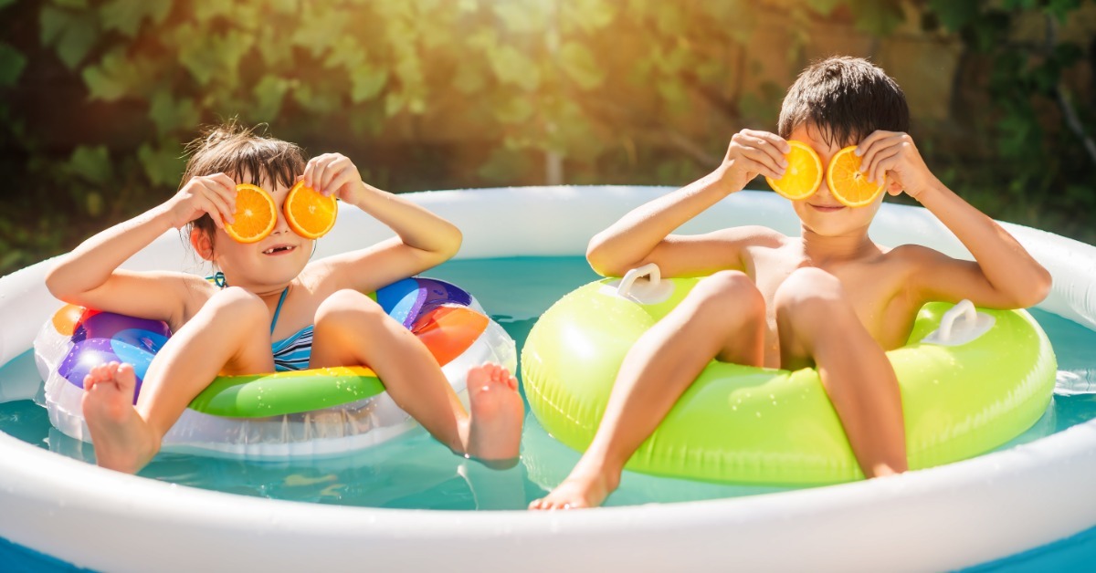 Two kids playfully posing while sitting in inflatable pool floats within an inflated kiddie pool in their backyard. Two kids playfully posing while sitting in inflatable pool floats within an inflated kiddie pool in their backyard.