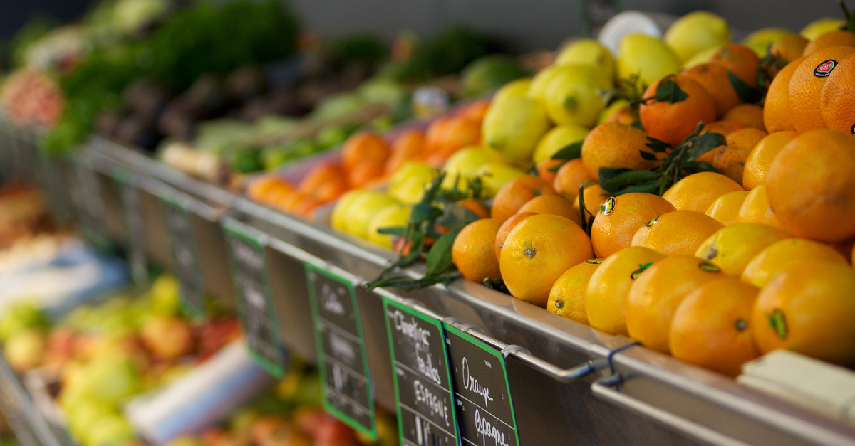 A close-up of the produce section of a supermarket showing various fruits like oranges, lemons, and more.