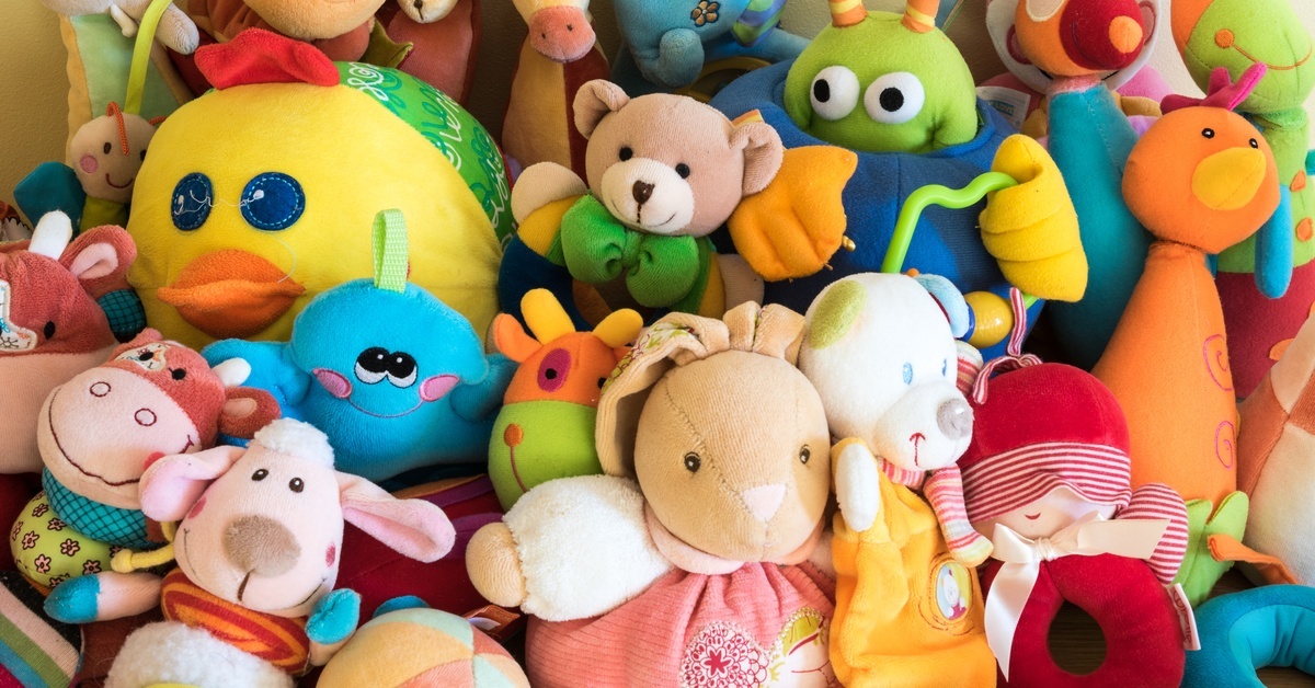 A close-up of a pile of children's stuffed animals and toys, including dogs, cows, ducks, volleyballs, and more.