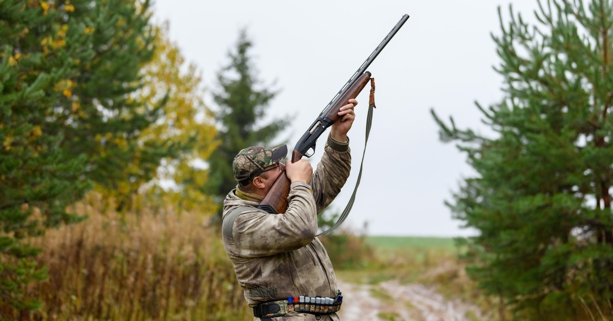 A person using a green brush to polish the barrel of a hunting rifle. They are holding the equipment carefully outside.